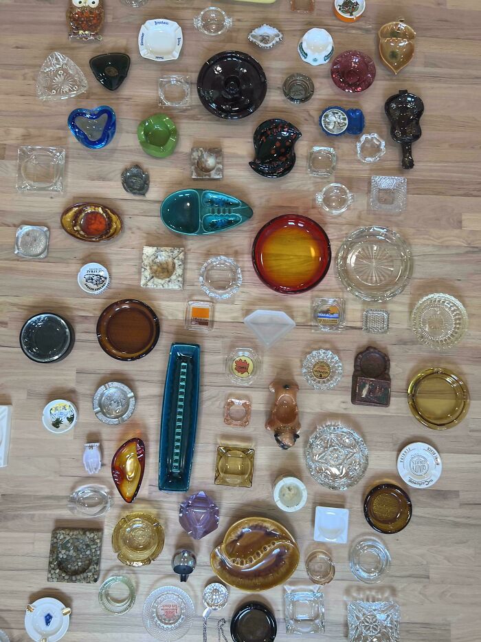 An overhead view of a diverse and fascinating collection of ashtrays of different sizes, materials, and colors.