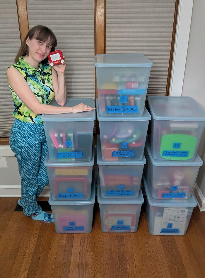 A smiling woman stands beside a tall stack of clear plastic storage containers, each filled with fascinating collections.