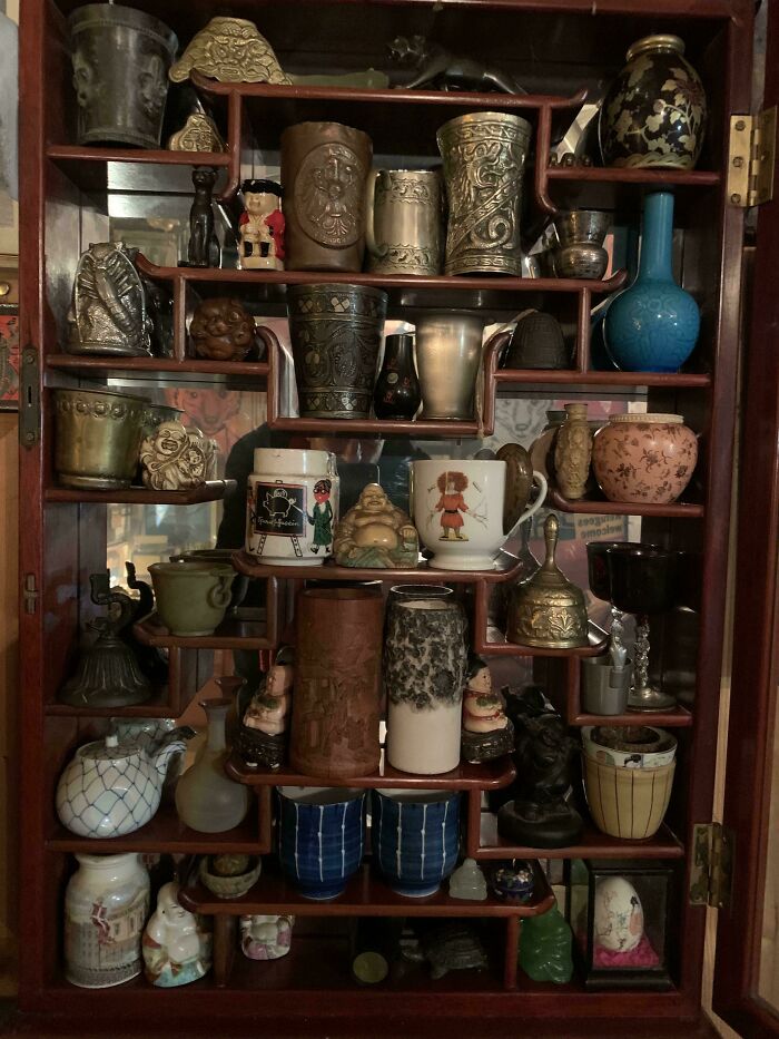 An antique wooden display cabinet filled with a fascinating collection of various small vases and trinkets.