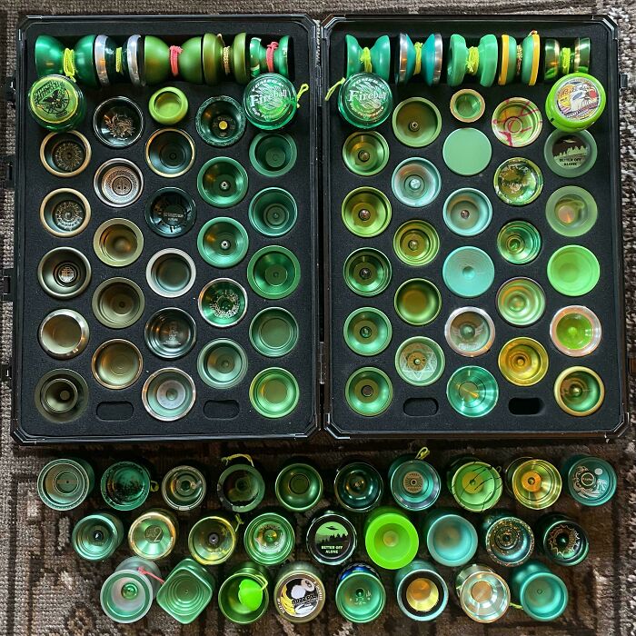 A fascinating collection of green yo-yos neatly arranged in cases and spread on a rug, demonstrating a dedicated hobby.
