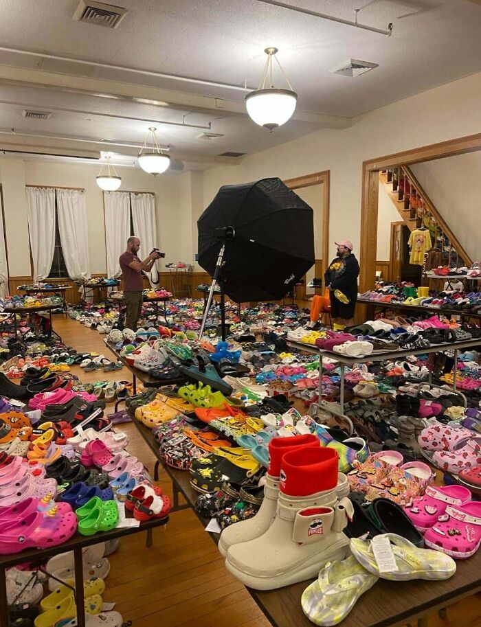 A large room filled with an immense, fascinating collection of colorful Crocs shoes, displayed on tables and floor.