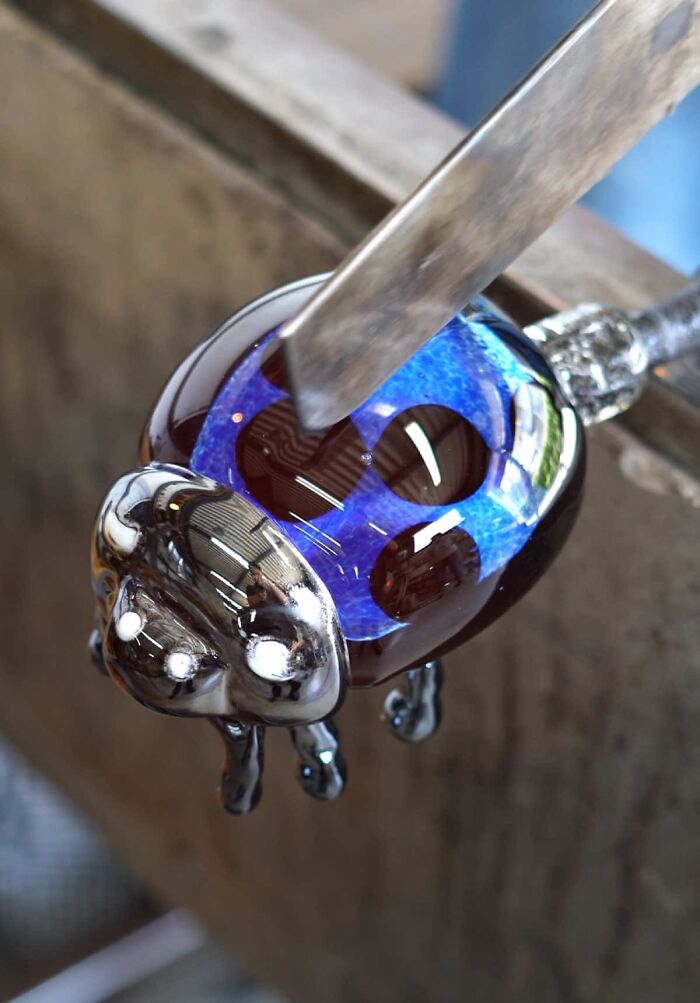 Japanese artist creates hyper-realistic glass food, a ladybug-like glass sculpture with blue and black patterns.