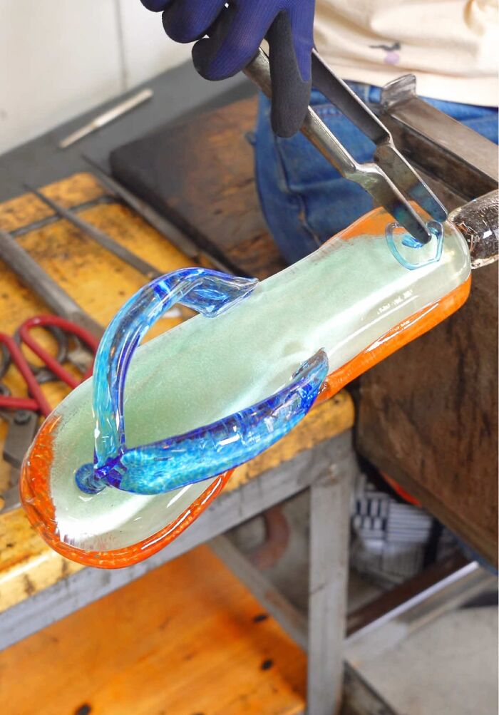 Japanese artist creates hyper-realistic glass food, a flip-flop shaped glass sculpture with blue straps.