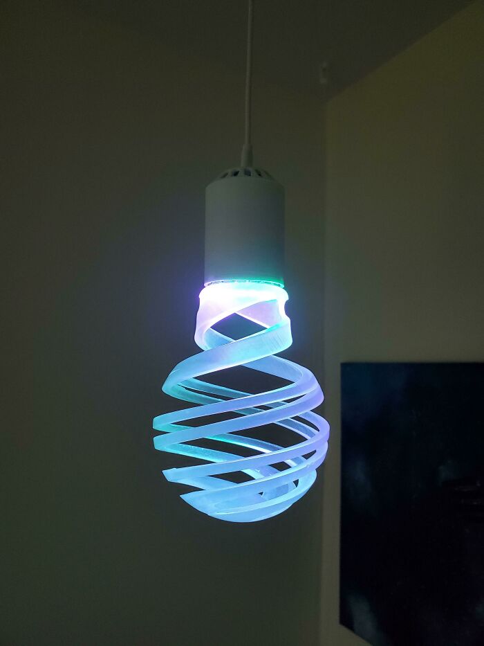 A glowing, spiral-shaped functional 3D print light bulb, making everyday life much easier with its unique design.