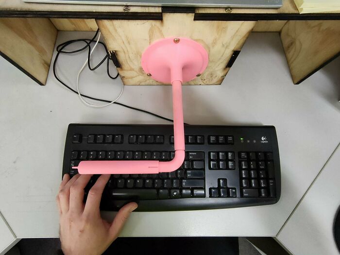 A hand using a keyboard with a pink functional 3D print attached, making everyday life much easier.
