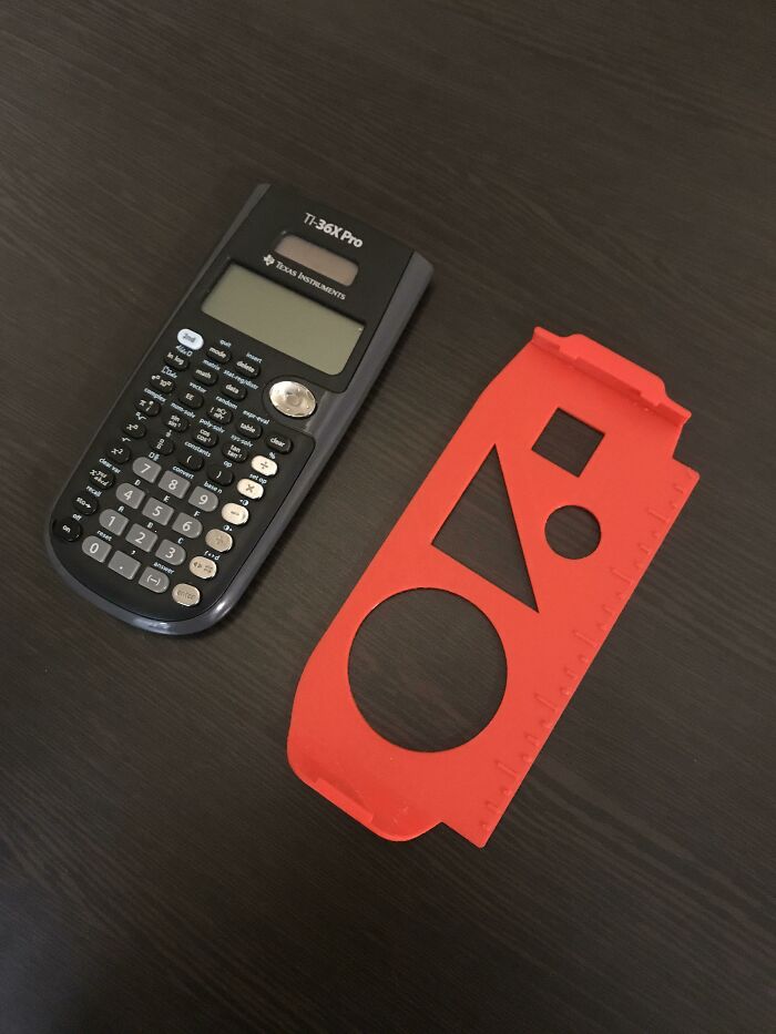 A black TI-36X Pro calculator next to a red 3D printed ruler cover with cutouts for shapes, a useful 3D print.