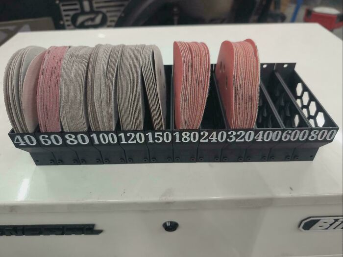 A black 3D print organizer filled with sanding discs of various grits, demonstrating functional 3D prints.