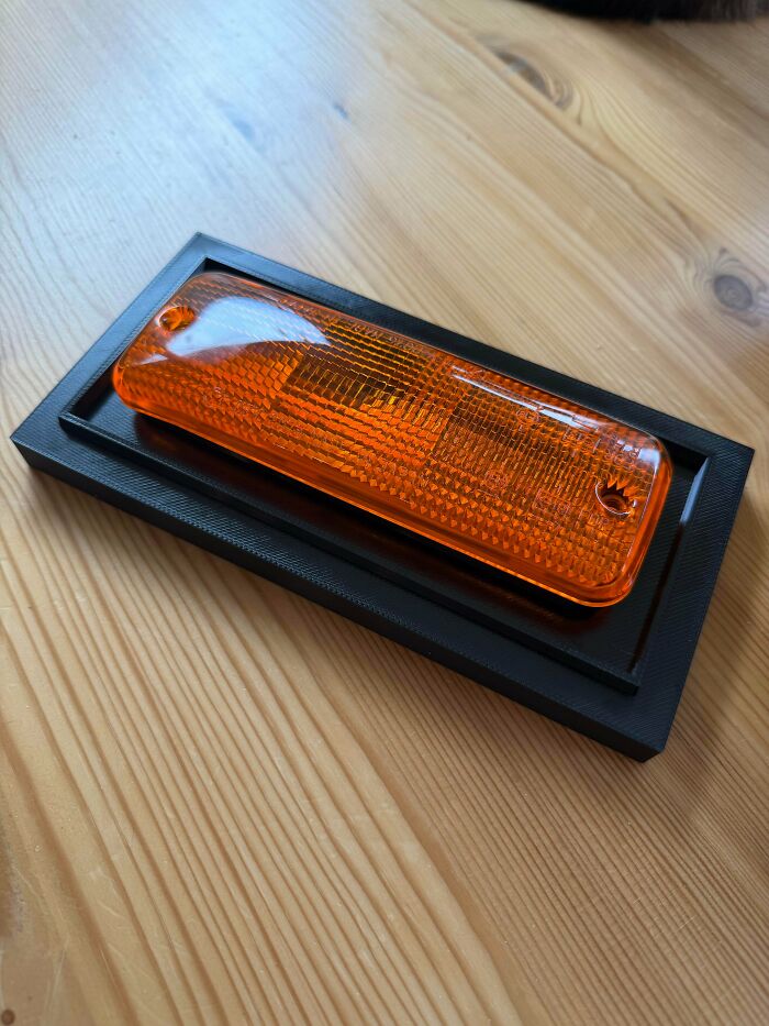 An orange car indicator light resting on a black 3D print base, a functional 3D print for easier everyday life.