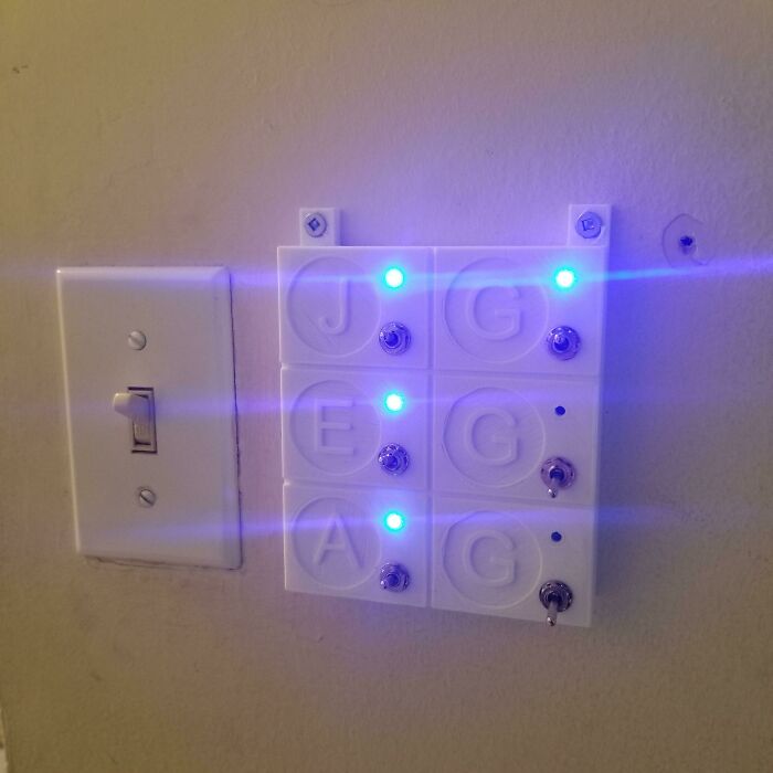 A custom-built functional 3D print light switch panel with LED lights next to a standard switch for everyday life.