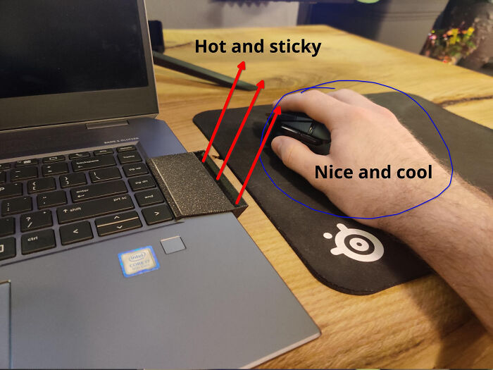 A hand on a cool mouse next to a laptop with functional 3D prints, making everyday life much easier.