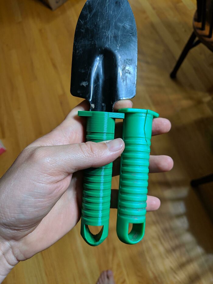 A hand holding a garden trowel with a green functional 3D print handle, making everyday life easier.