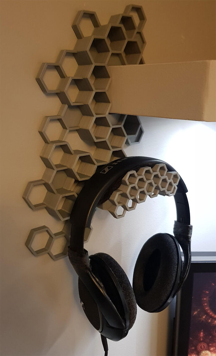 A stylish, functional 3D print: a honeycomb-patterned wall mount holding a pair of headphones.