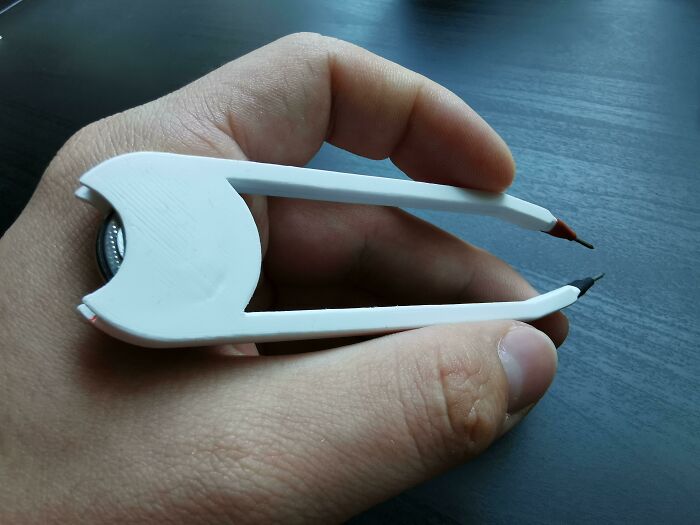 A hand holding a white 3D print tool with two sharp ends, designed to make everyday life much easier.