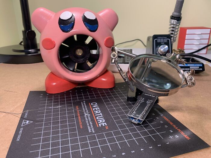 A functional 3D print of a Kirby character housing a fan, with a magnifying tool beside it, making everyday life easier.