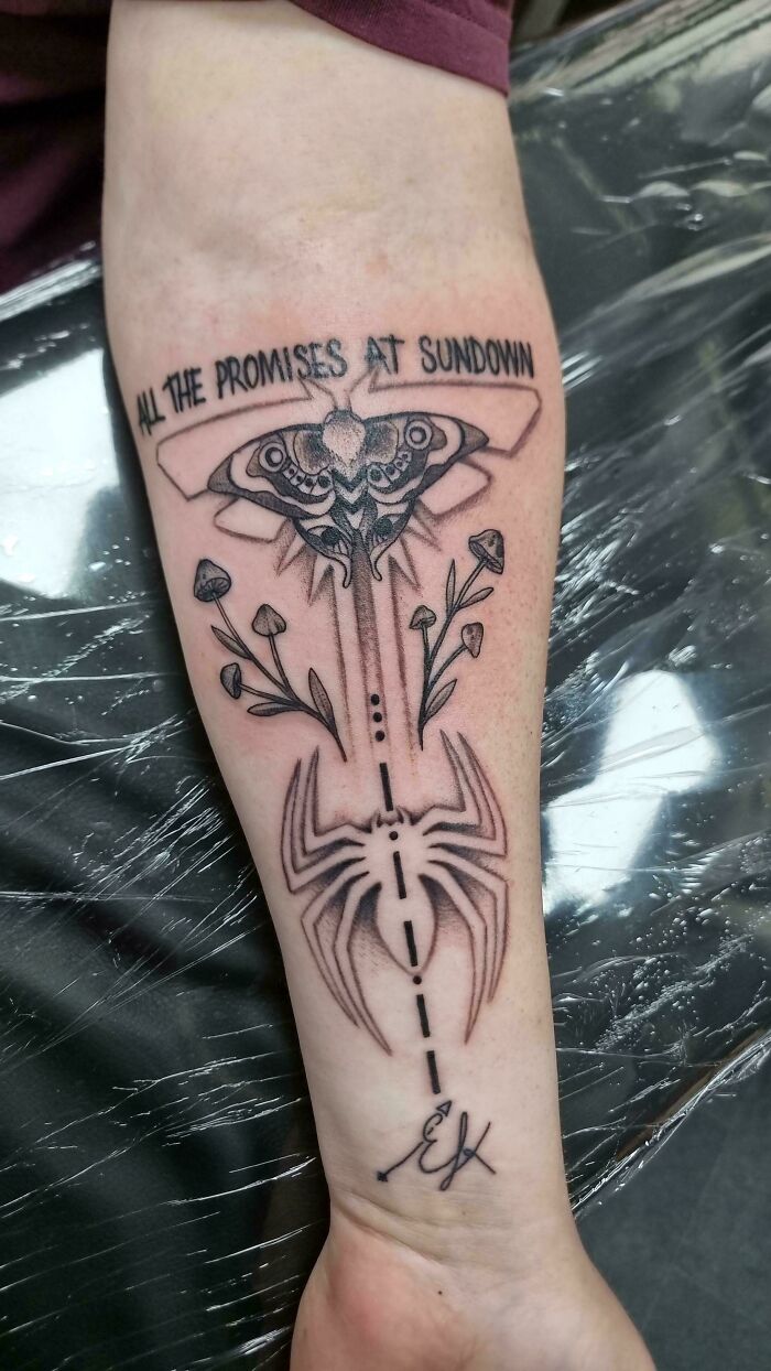 A tattoo artist's work showcasing a moth, spider, mushrooms, and text on a person's arm, a questionable tattoo idea.