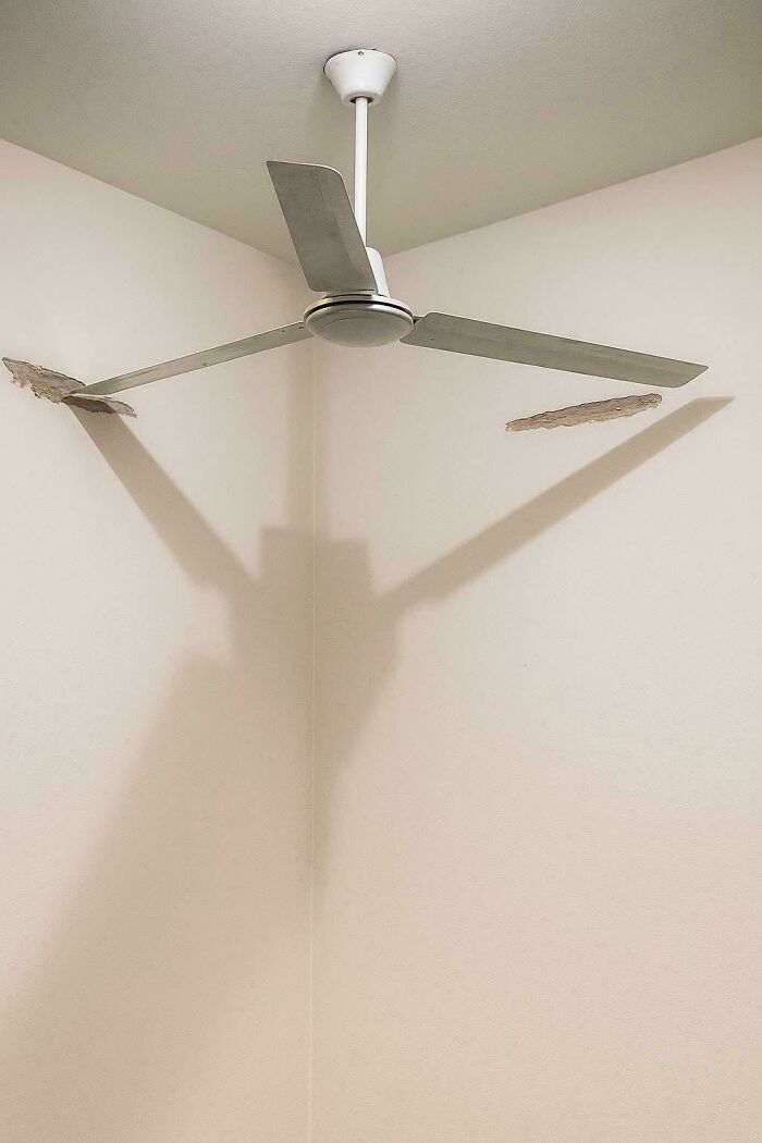 A ceiling fan installed precariously in a room corner, demonstrating a ridiculous common sense fail.