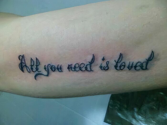 A misspelled tattoo reading All you need is loved instead of All you need is love, a You Had One Job fail.