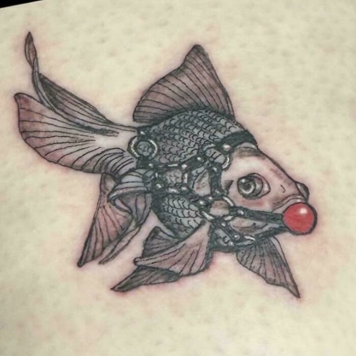 A detailed tattoo of a goldfish wearing a ball gag, showcasing a tattoo artist's questionable ideas.