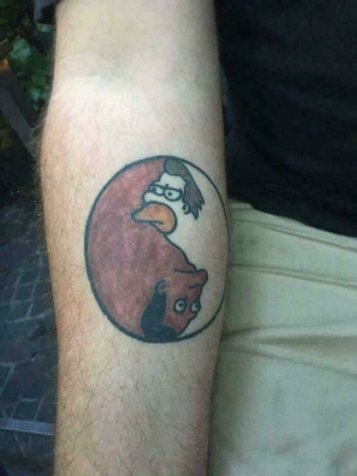 A unique tattoo on a person's forearm, featuring a yin and yang symbol with Homer Simpson and Peter Griffin. An example of a questionable tattoo idea.