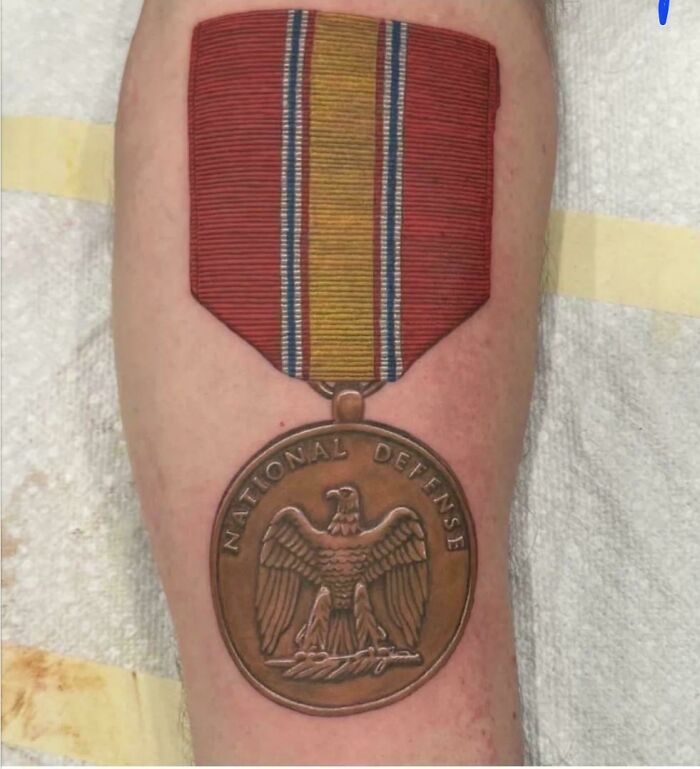 A realistic tattoo of a National Defense Service Medal on an arm, highlighting a tattoo artist's talent.