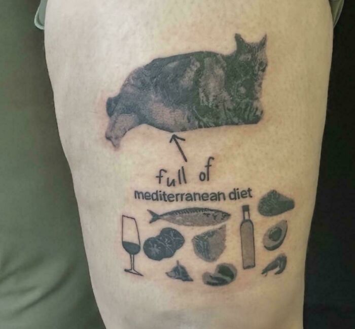 A cat tattoo with an arrow pointing to a Mediterranean diet food illustration, a questionable tattoo idea.