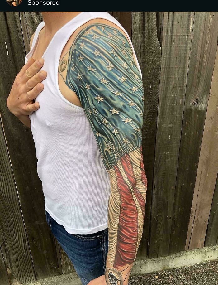 A tattoo artist's work on a full sleeve tattoo with questionable ideas featuring a detailed American flag, showcasing patriotic artistry.