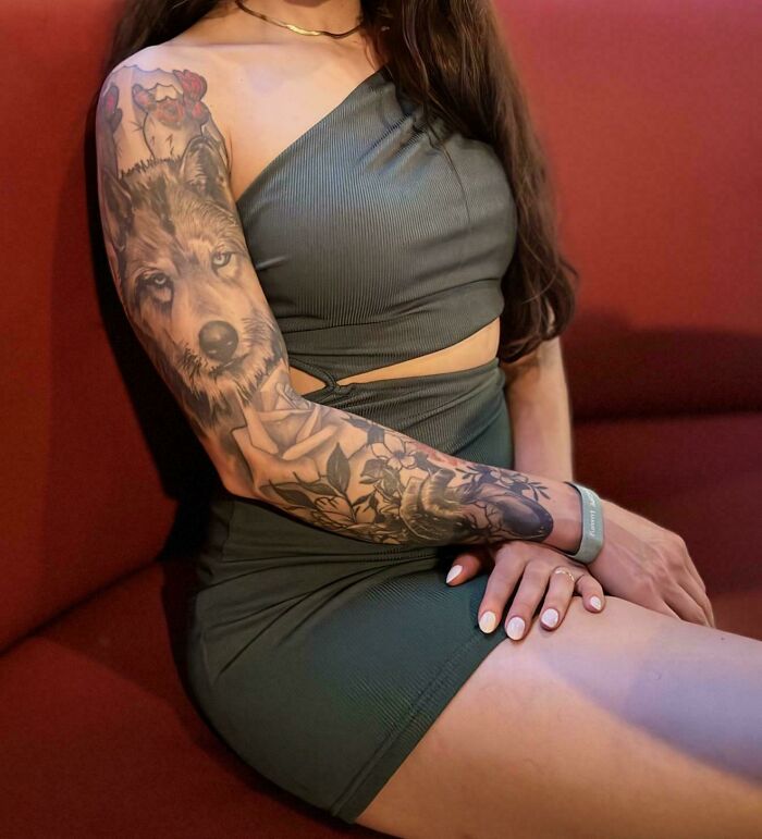 Woman in dress showing a wolf tattoo artist sleeve, questionable ideas.
