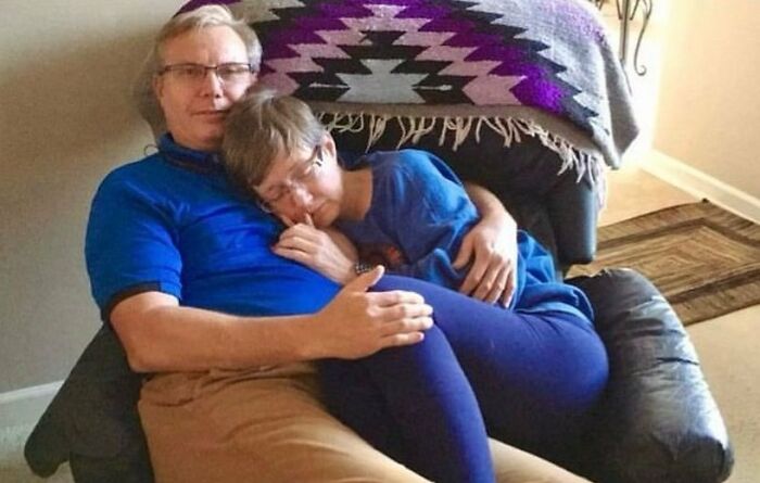A couple cuddling in a chair, a woman sleeping peacefully on the man's lap, a soul-healing moment.