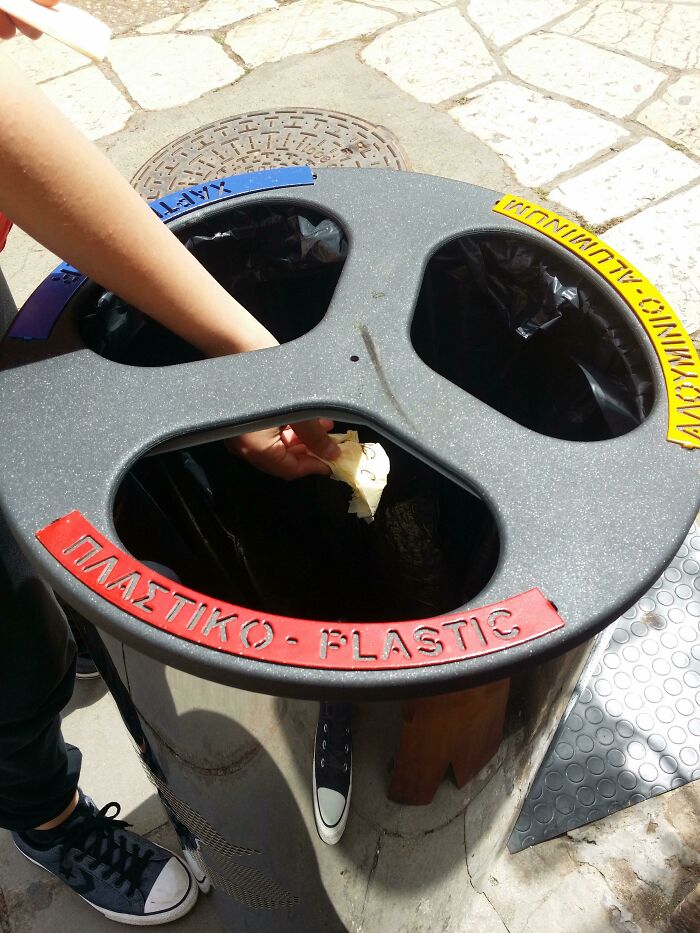 A hand placing trash into a recycling bin with labels in the wrong order, showing a You Had One Job fail.