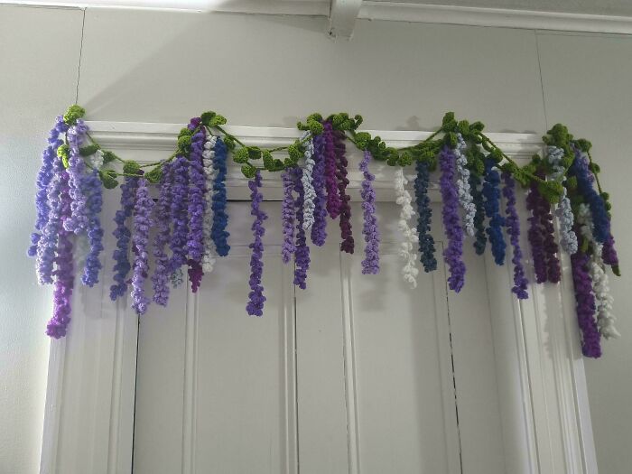Crochet enthusiasts' wisteria garland in purple, blue, and white, an incredible handmade decoration over a doorway.
