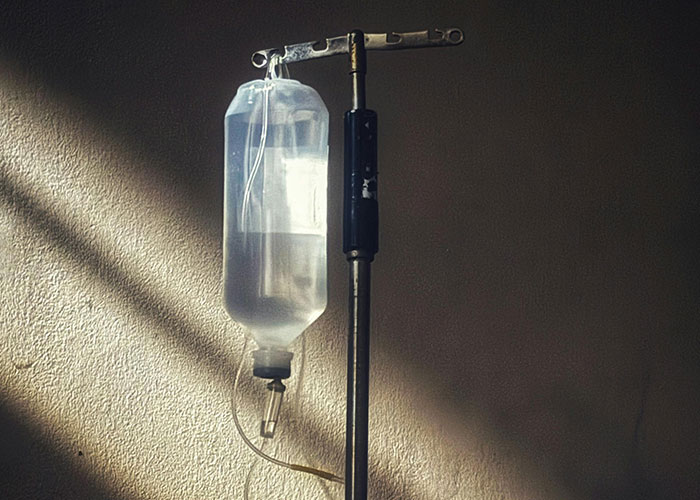 Intravenous drip bag hanging on pole in dimly lit room related to secrets people take to their graves