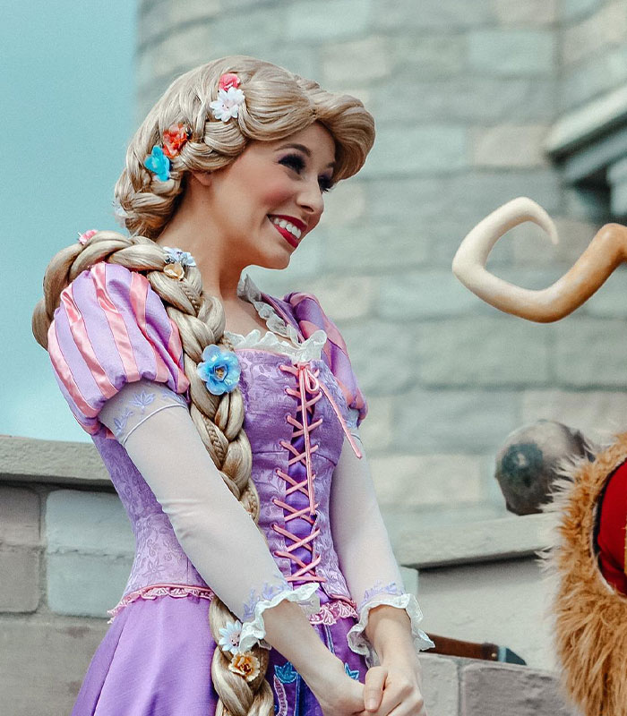 Disney princess Rapunzel costume character smiling outdoors at theme park Disney princess Rapunzel costume character smiling outdoors at theme park