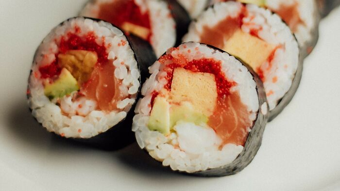 Close-up of sushi rolls with avocado, fish, and roe filling