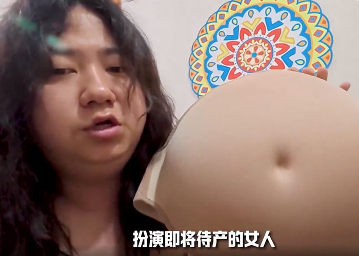 Korean man holding a prosthetic pregnant belly to expose gender violence