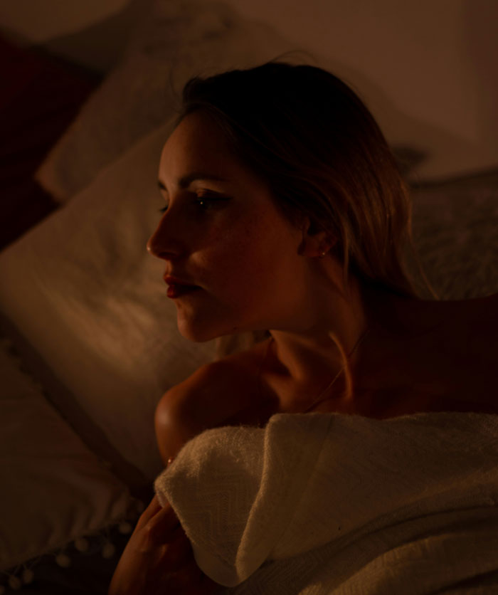 Woman wrapped in blanket lying down in dim light