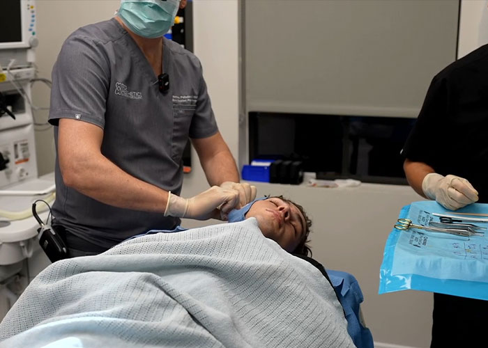 Doctor performing looksmaxxing procedure on patient in clinic setting Doctor performing looksmaxxing procedure on patient in clinic setting