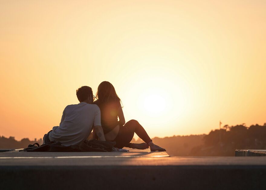 Couple sitting together watching sunset sharing intimate moment outdoors