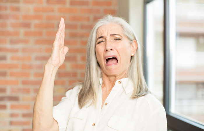 Older woman yelling with raised hand in Karen parent stereotype