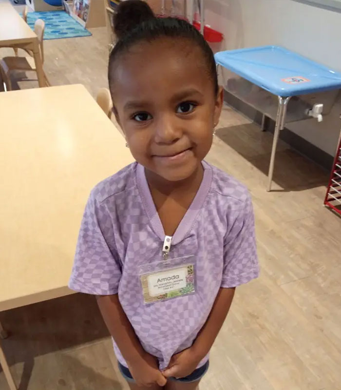 Young girl wearing a name tag inside a room, smiling at camera Young girl wearing a name tag inside a room, smiling at camera