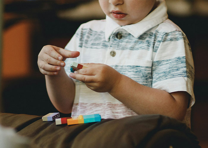 A young boy with short hair holding colorful building blocks, representing the understanding of autism. A young boy with short hair holding colorful building blocks, representing the understanding of autism.