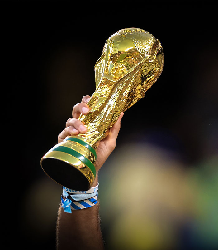 A hand holds the World Cup trophy, symbolizing the success and luxury associated with wealthy star players and their companions.