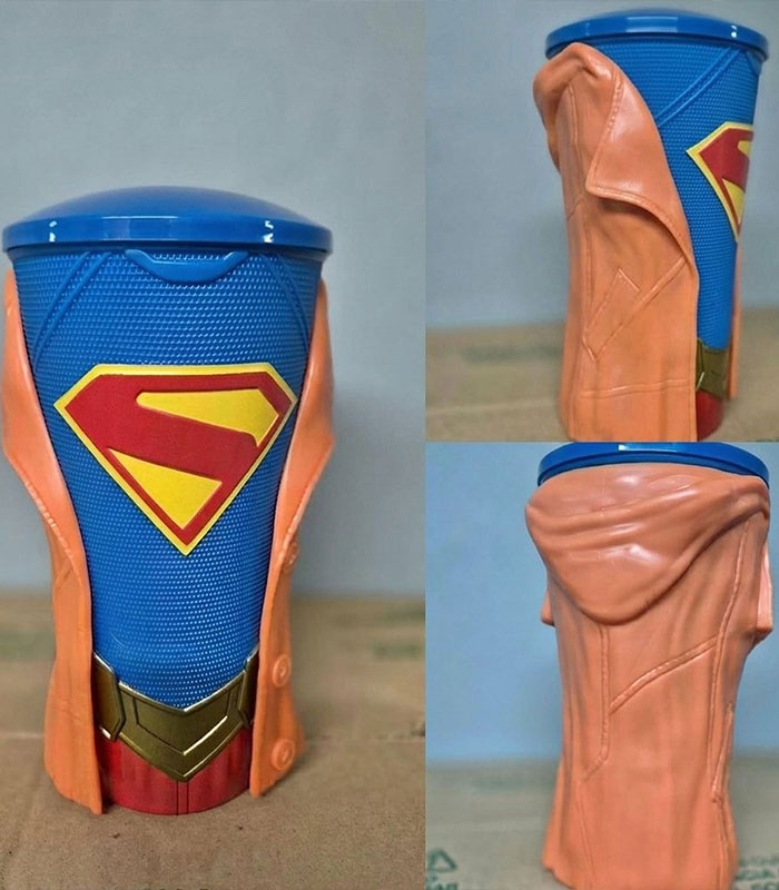 A Supergirl movie souvenir, a blue cup with a yellow and red S-shield and an orange trench coat design.