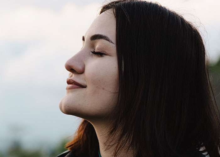 A young woman with dark hair smiles with her eyes closed, reflecting on family advice.