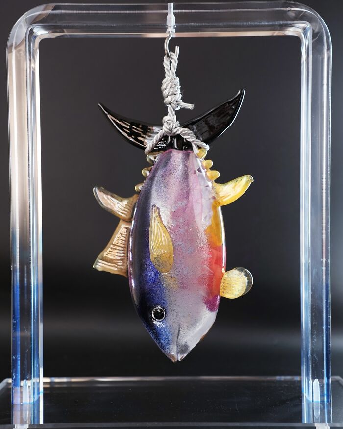 A vibrant, hyper-realistic glass food fish, an artist's creation, hanging within a clear frame, looking good enough to eat.