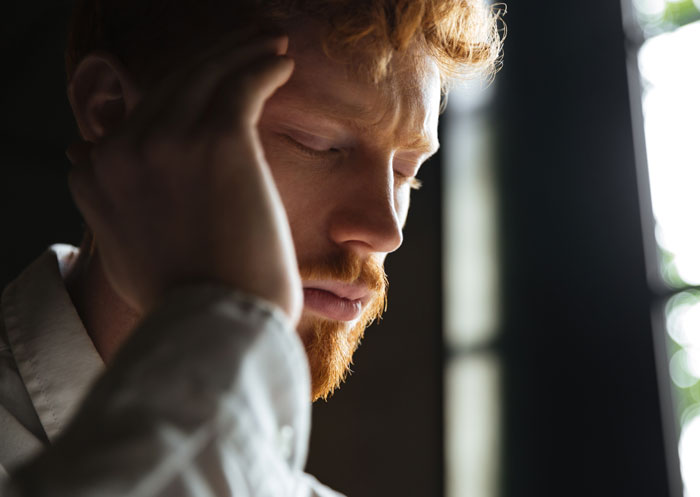 Man holding his head appearing stressed and emotional Man holding his head appearing stressed and emotional