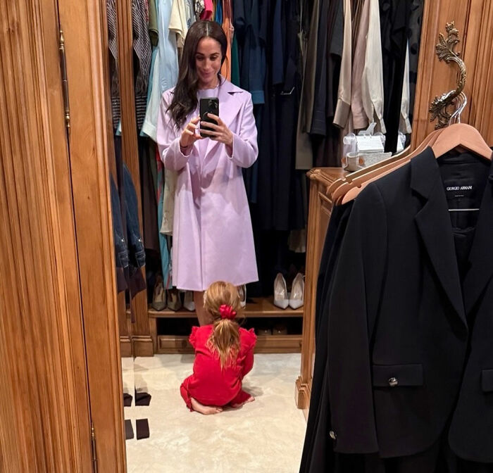Meghan Markle taking mirror selfie with child in red outfit