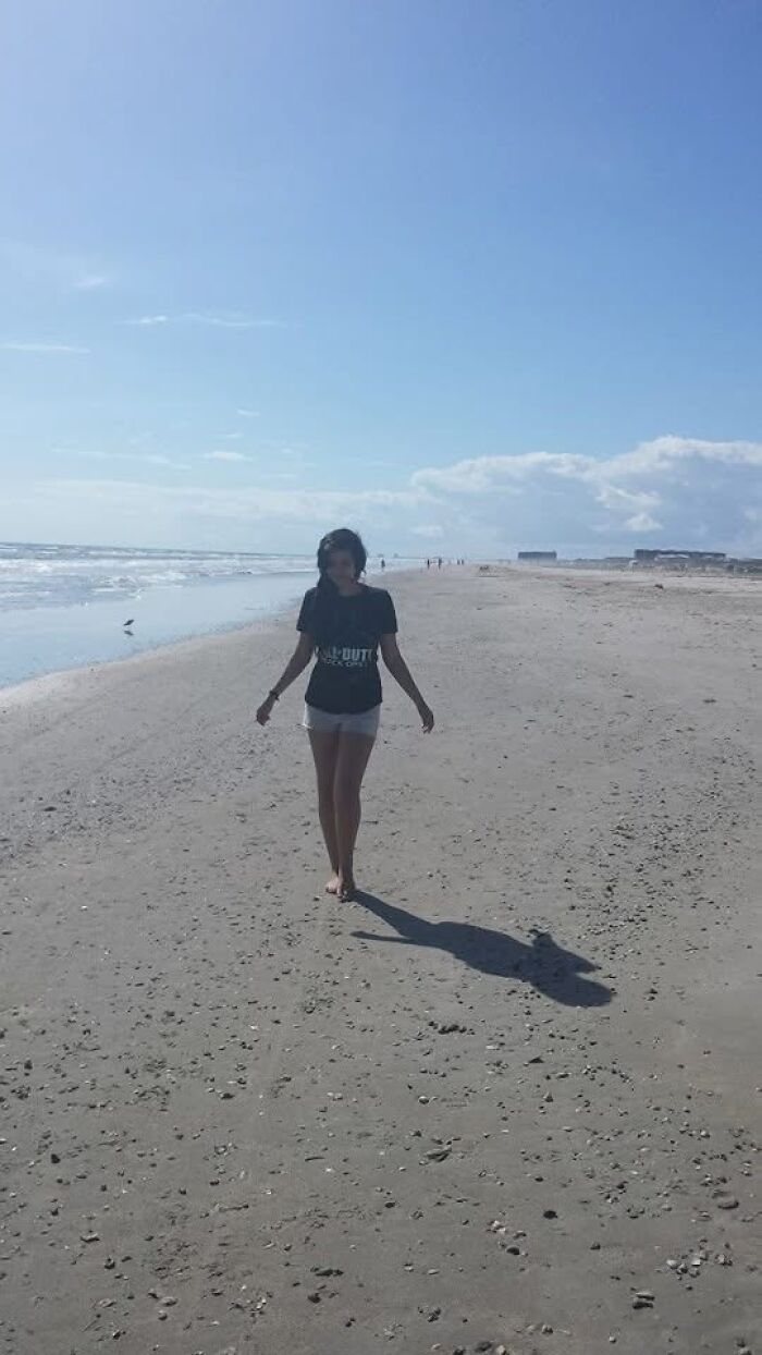 Woman walking alone on beach under blue sky