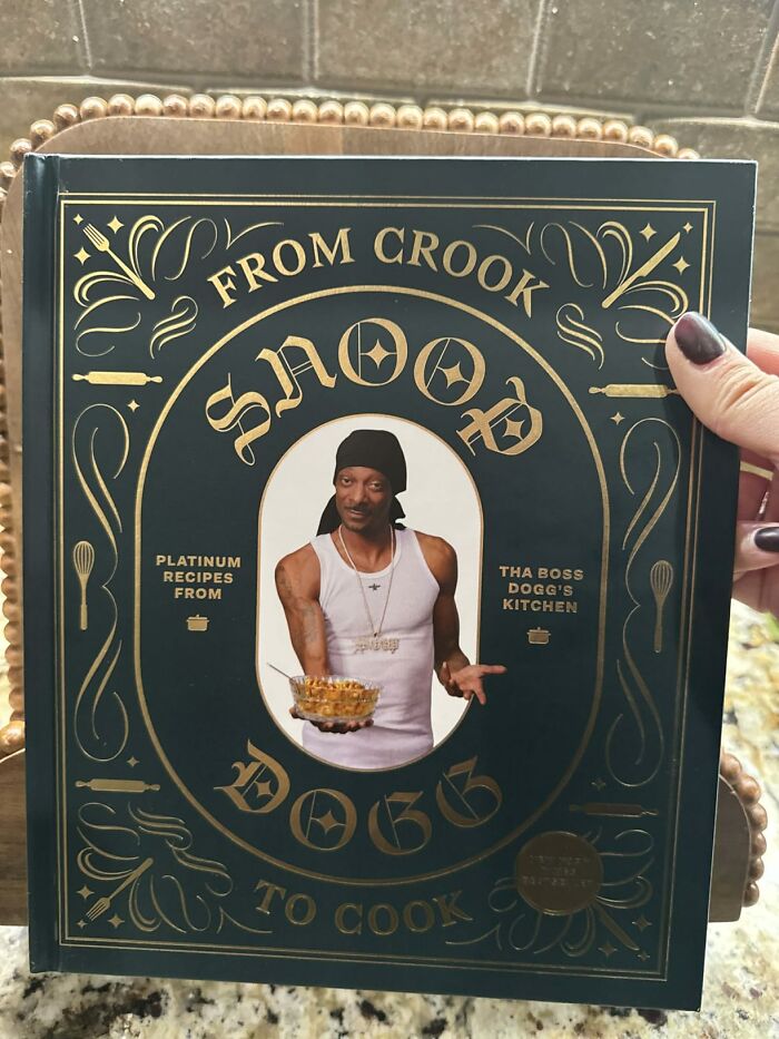 Snoop Dogg cookbook titled From Crook to Cook held by person with dark nail polish, unique father's day gift