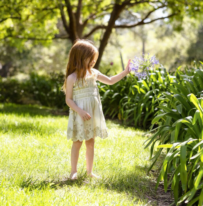 Lilibet playing barefoot outdoors holding flowers