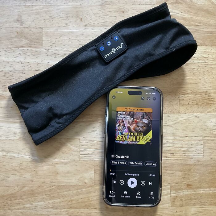 A black Musicozy sleep headband next to a smartphone playing an audiobook, highlighting Prime Day electronics deals.